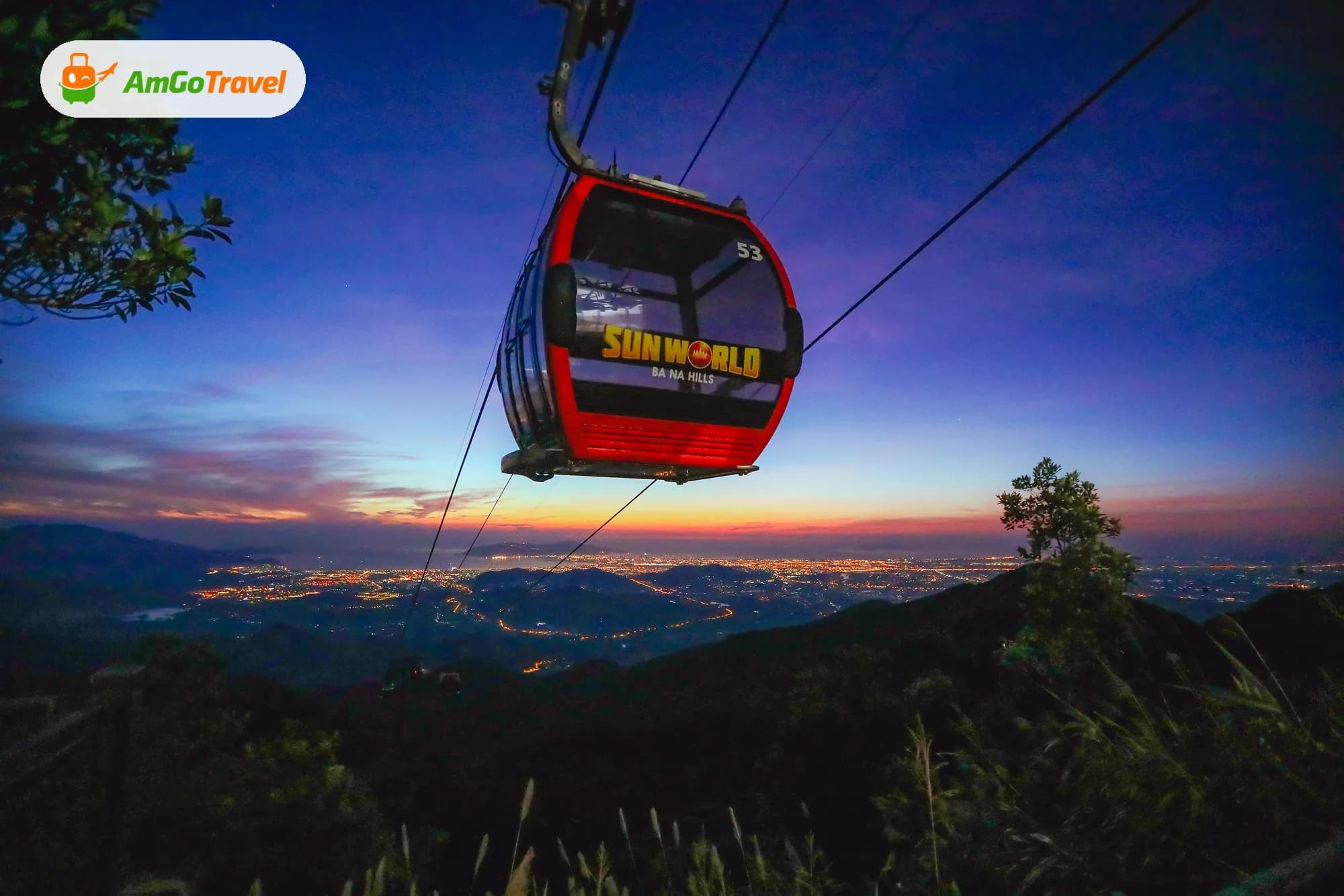 Cabin cáp treo Bà Nà trên rừng lúc hoàng hôn, phía xa là ánh đèn Đà Nẵng